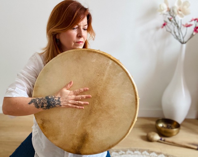 une femme avec un tambour avec au fond un bol tibétain